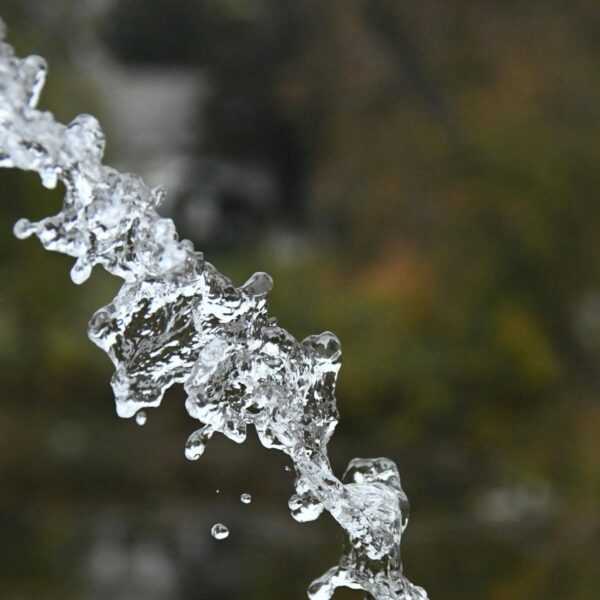 Captivating shot of a water stream in motion against a blurred background, emphasizing purity and fluidity.