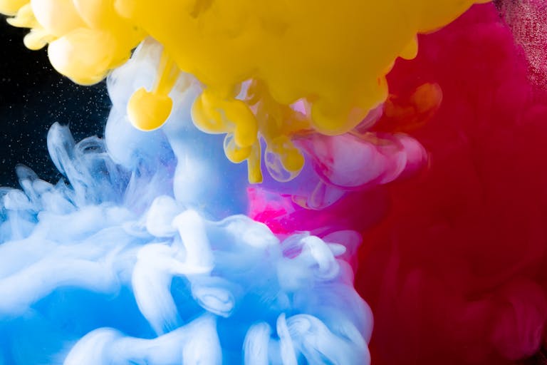 Dynamic underwater ink explosion with vibrant colors creating a mesmerizing abstract art piece.