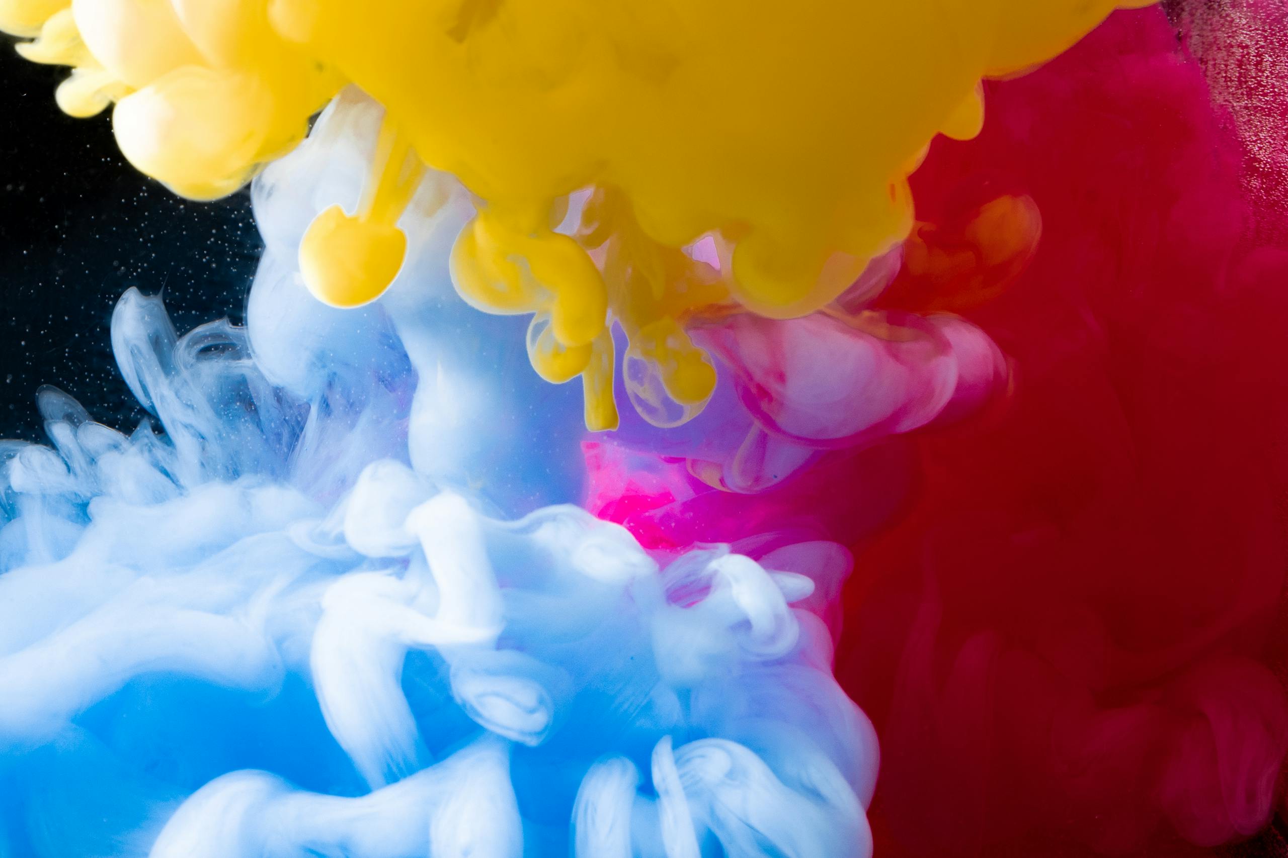 Dynamic underwater ink explosion with vibrant colors creating a mesmerizing abstract art piece.